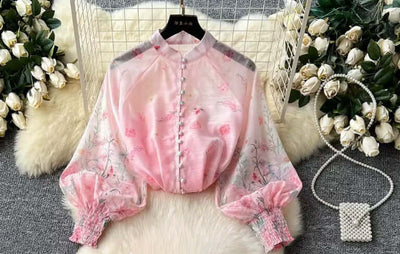 Pink slim-fit top with lantern sleeves and floral design, featuring button details and elegant style for women.